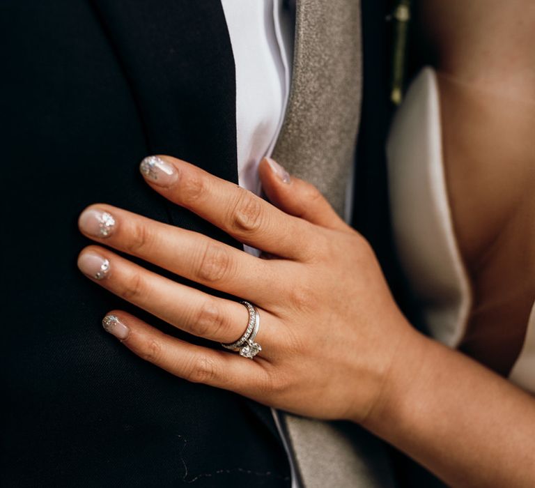 Classic platinum and diamond wedding rings worn by bride with sparkly wedding nails 