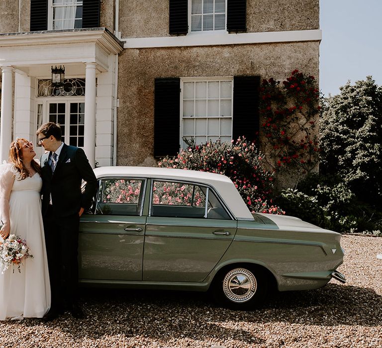 Vintage green wedding car in front of the Kent wedding venue with the bride and groom 