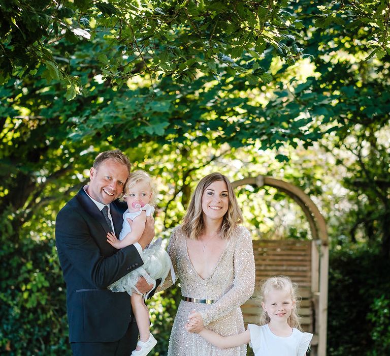 The bride and groom pose with their children in tutu dresses as flower girls