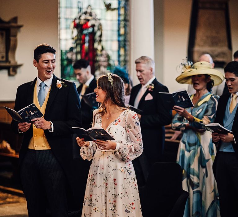 The bride and groom sing wedding hymns at church ceremony 