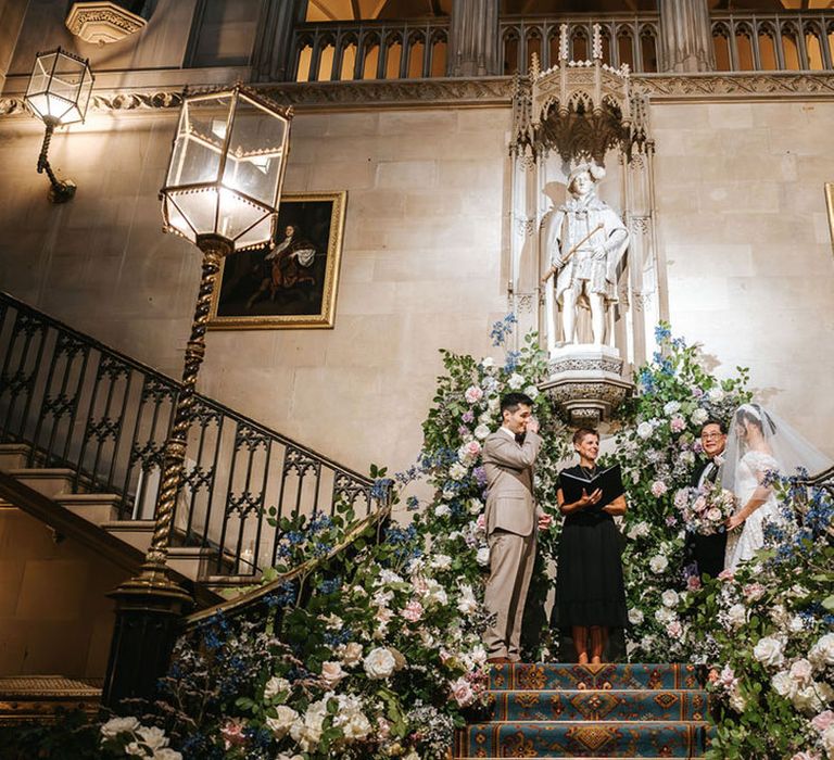 Wedding ceremony on the stairs at Ashridge House with pastel wedding flower aisle decorations 