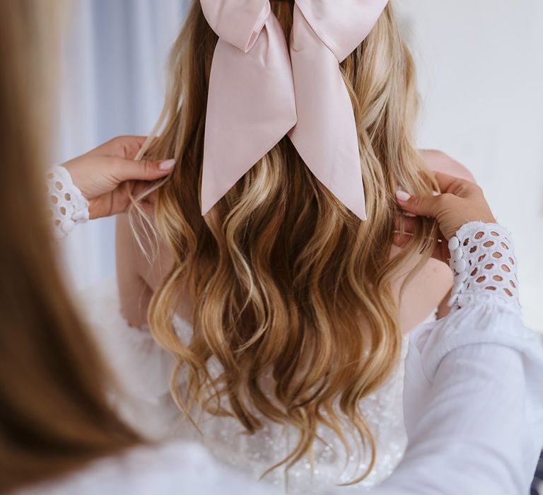 Bride wearing half up half down hair with pink bow hair accessory for wedding 