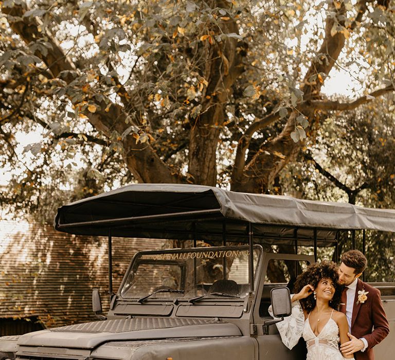 Black safari jeep at Port Lympne wildlife reserve with the bride wearing boho lace wedding dress with red wedding suit 