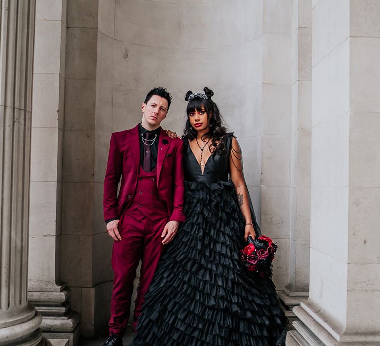 Bride wearing black ruffled wedding dress and groom in dark red velvet suit for gothic theme wedding 