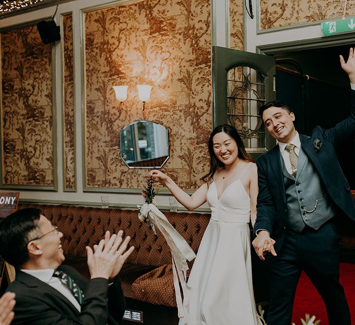 Bride and groom entering their pub wedding reception at Balham Bowls Club