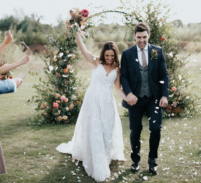 Bride and groom just married at outdoor wedding with floral moon gate 