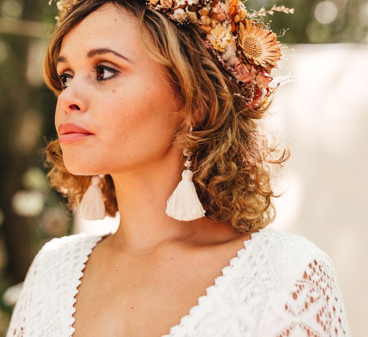 Boho chic bride wears white tassel earrings and flower crown