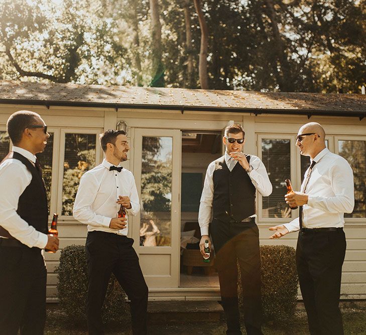 Groom and groomsmen have a drink whilst getting ready for wedding