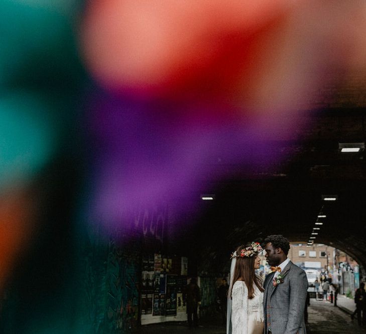 Wedding couple stand under city bridge