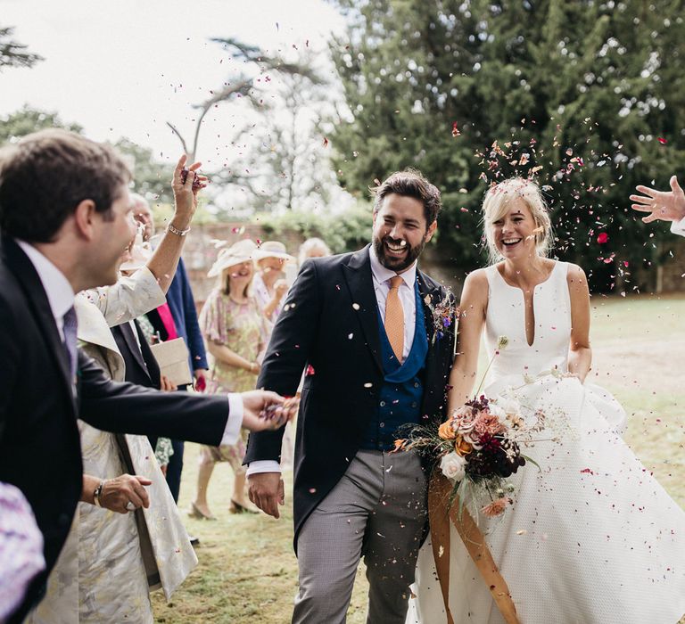 Confetti moment with the groom in a morning suit with blue horseshoe waistcoat and bride in a Jesus Peiro wedding dress 