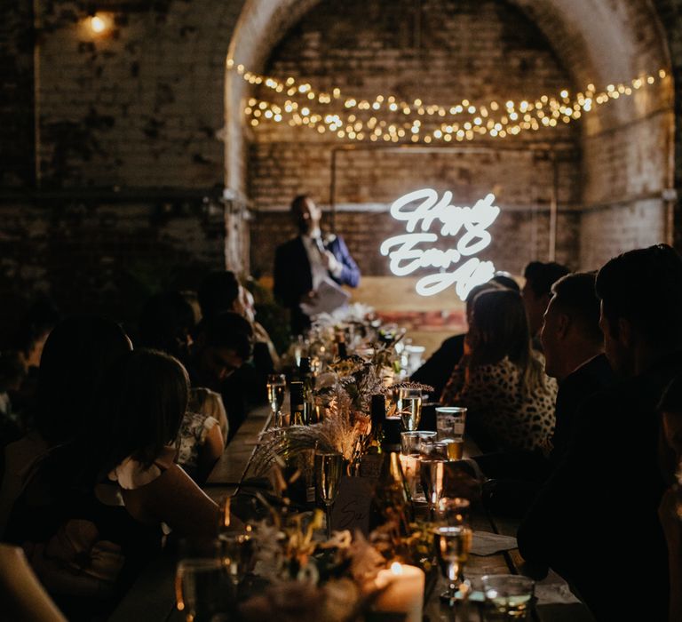 View down trestle table of guests while speeches are happening at the top