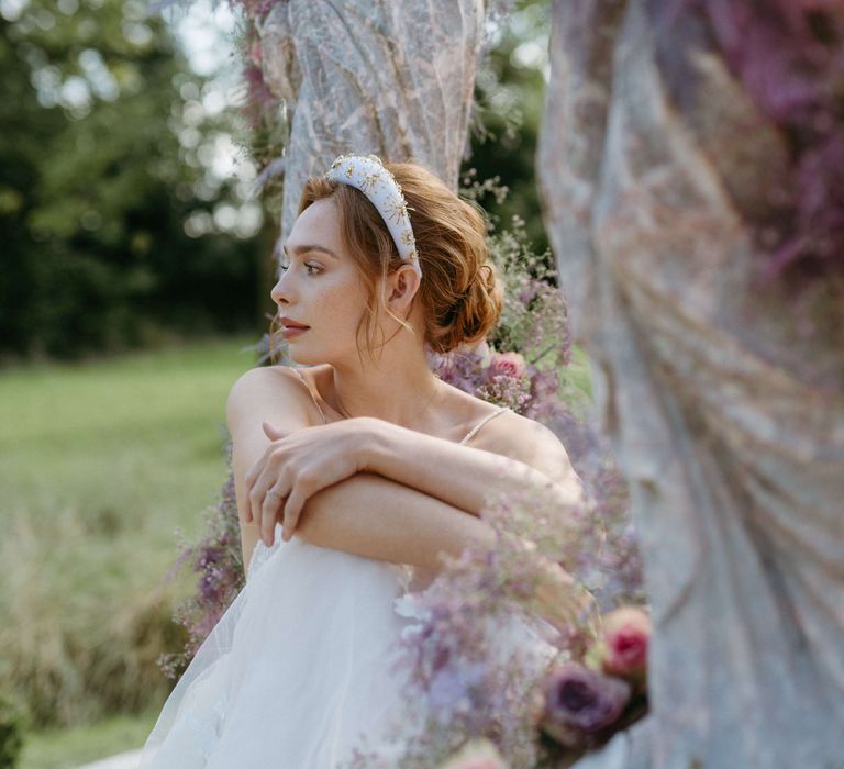 Bride wears white and gold headband whilst sat down