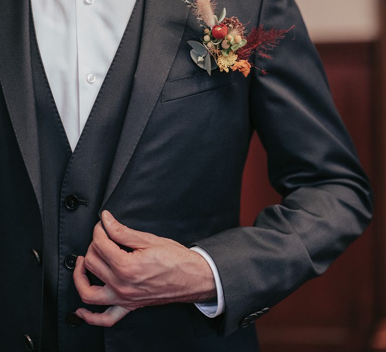 Groom wears suit with dried floral buttonhole 