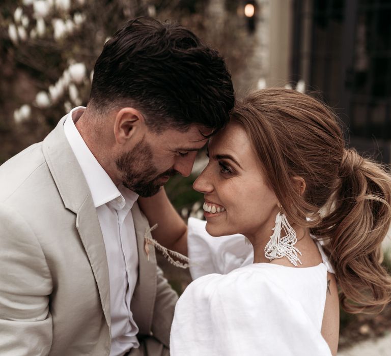 Bride with a wavy ponytail, puff sleeves and tassel earrings 