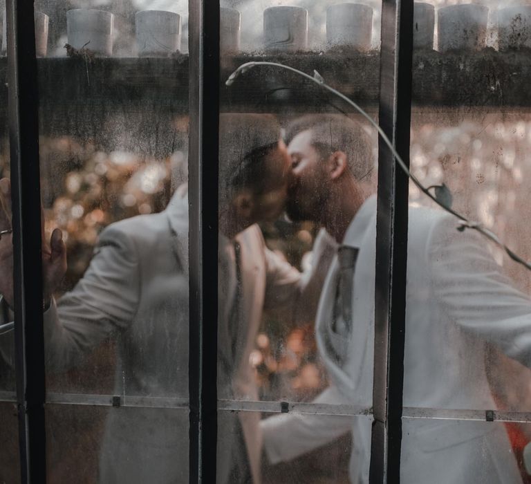 Grooms kiss in glass house