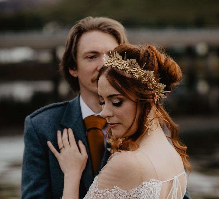 Bride looks down and behind her shoulder as groom holds her