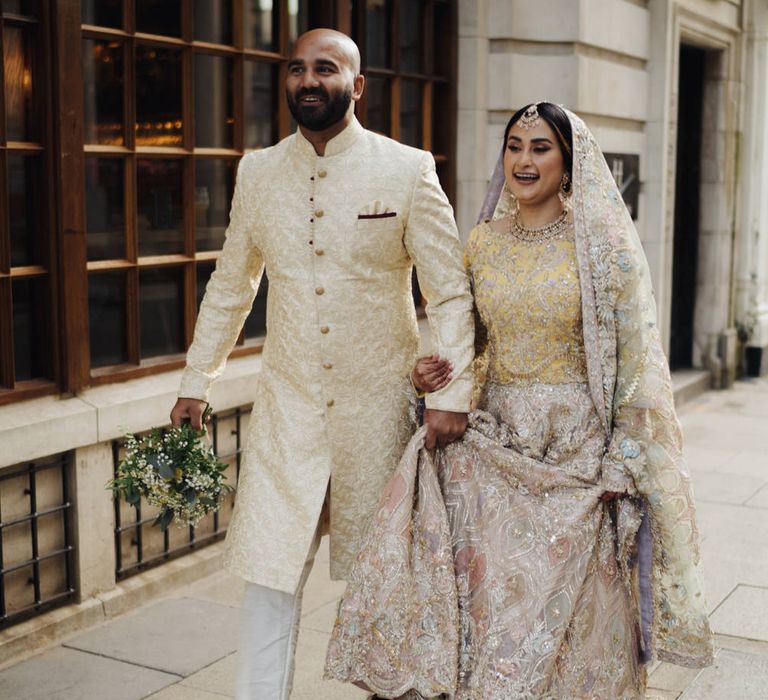 Islamic bride and groom walking down the streets of Birmingham in a pastel bengali's wedding dress and gold coat