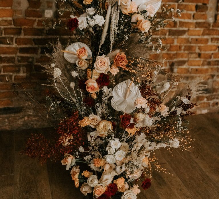 Tall floral decor made up of white, red, pink and blush roses, with pampas grass, wild flowers and white anthuriums