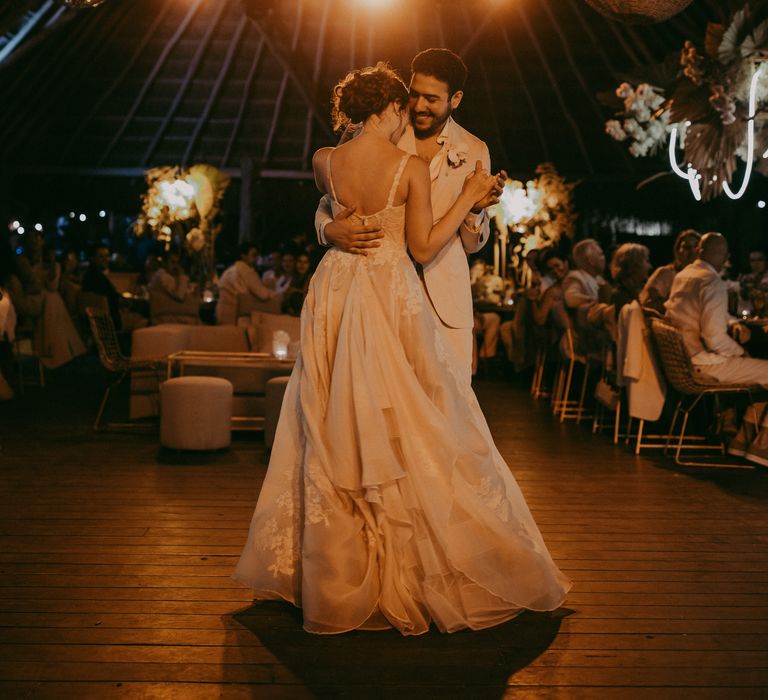 Bride & groom hold one another as they dance with one another during their wedding reception as the lights shine around them