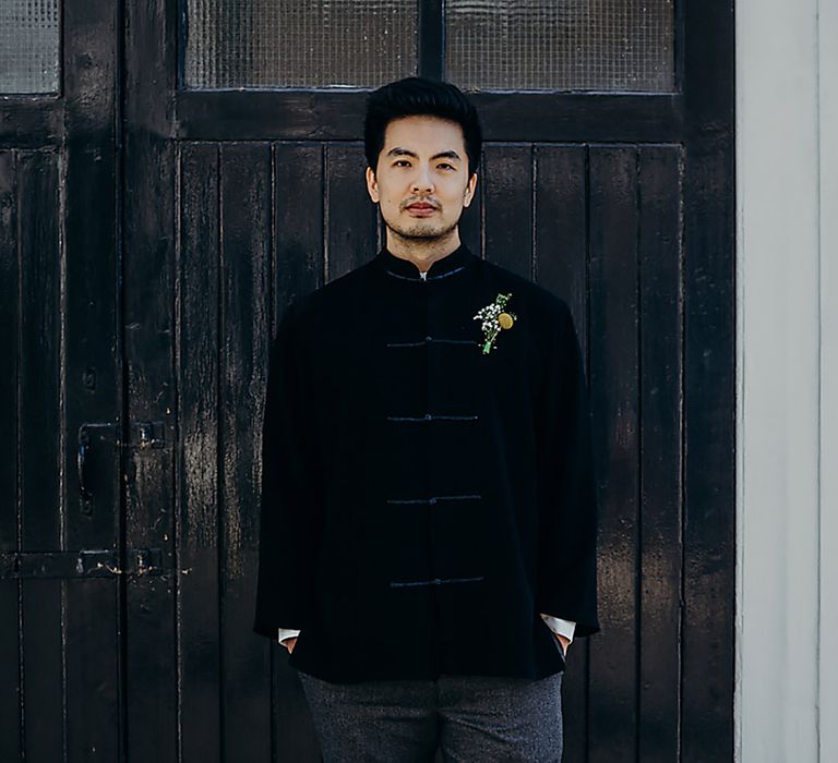 East Asian groom in a navy velvet jacket with yellow billy bob and gypsophila buttonhole flower 