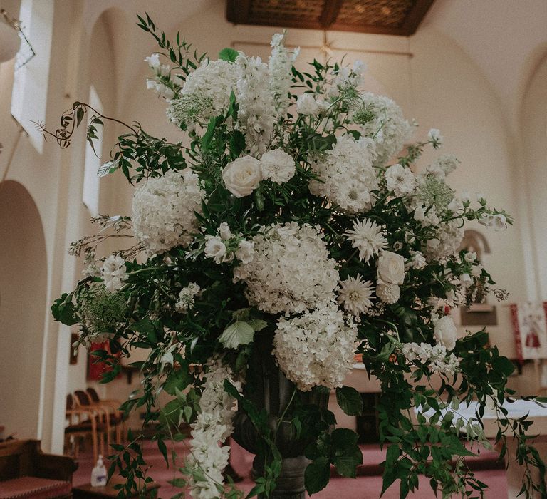 Large white and green floral display in church for Surrey summer wedding