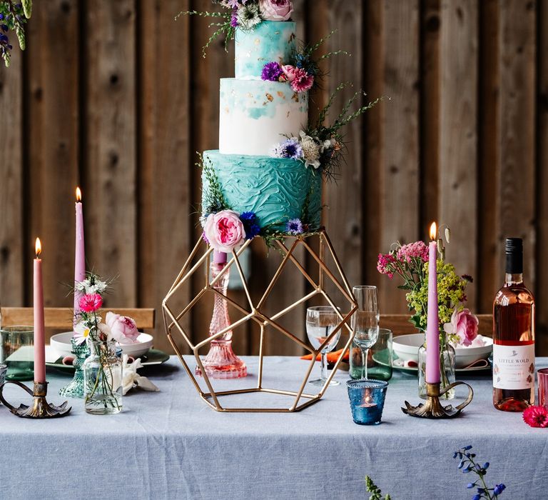 Turquoise and white buttercream wedding cake on a metal cake stand at the intimate wedding reception 