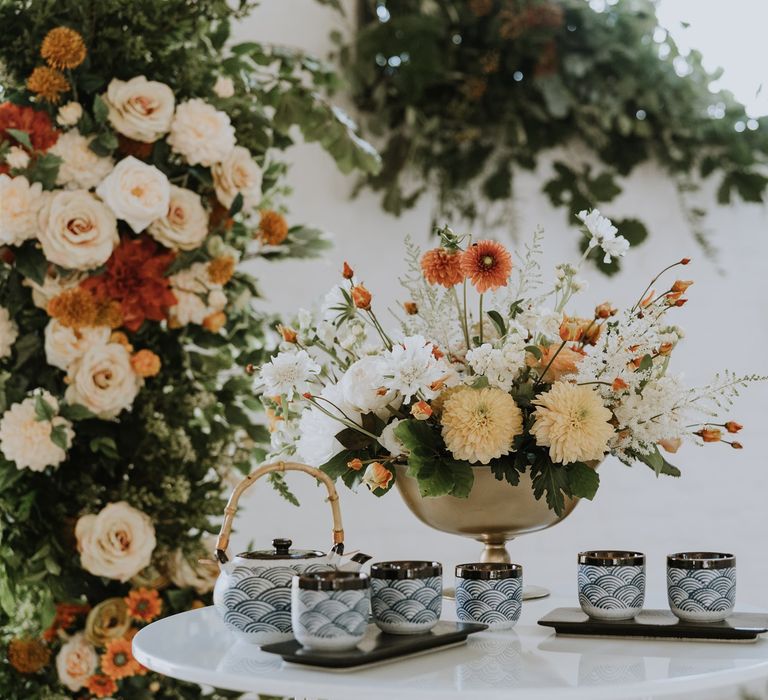 Chinese Tea Ceremony teapot and cups on a table with peach wedding floral arrangement 