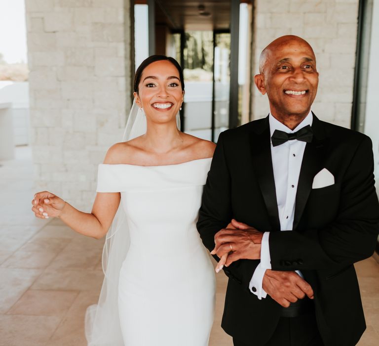 Bride walks arm in arm with her father on her wedding day as they both smile brightly | Hannah MacGregor Photo & Film