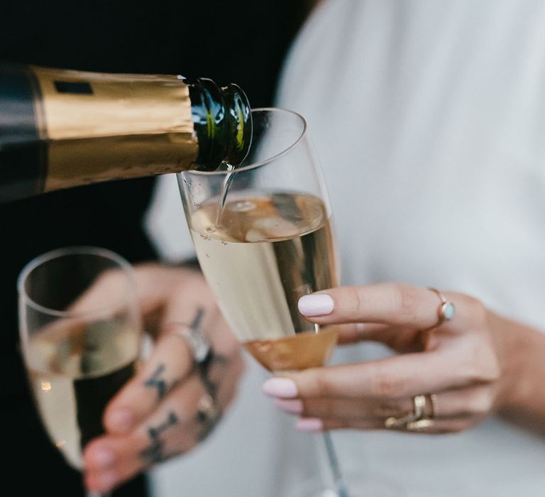 Bride with light pink wedding nails holding a flute champagne glass