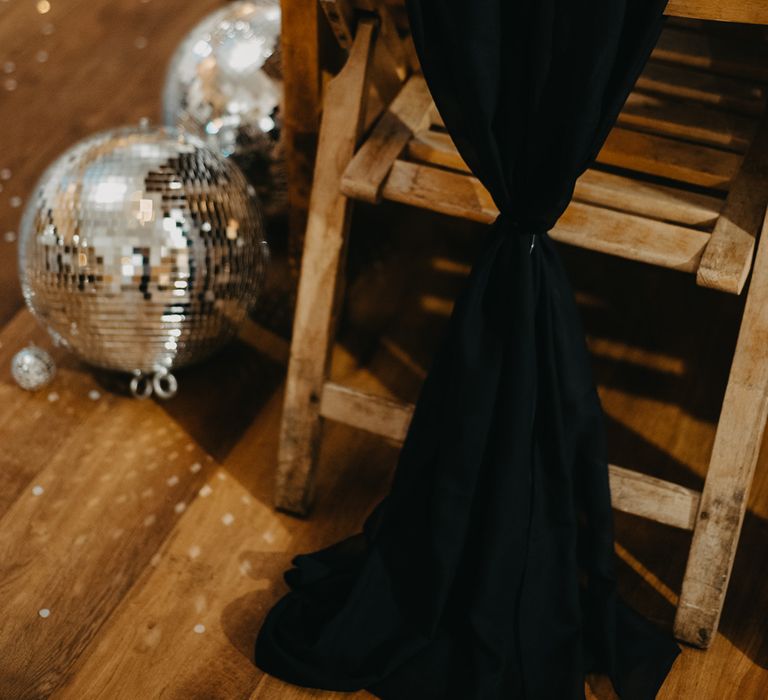 Wooden table and chair with black chair decor, disco balls and rustic tableware for Wellbeing Farm wedding in Lancashire