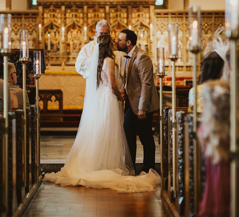 Bride & groom kiss during church ceremony on their wedding day 