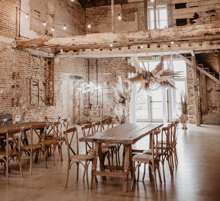 Godwick Barn complete with dried floral pampas grass installations and festoon lighting with wooden tables