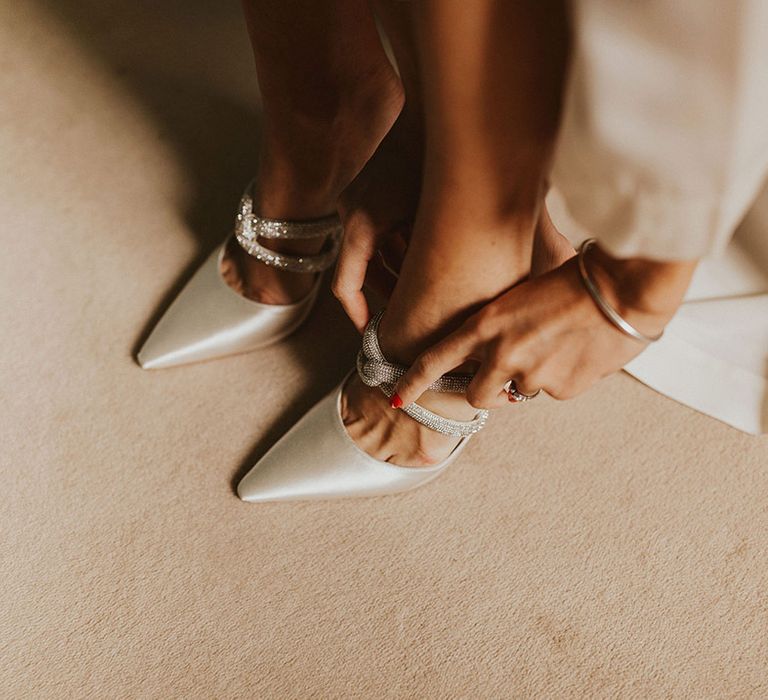 Bride puts on her wedding shoes with sparkling straps 