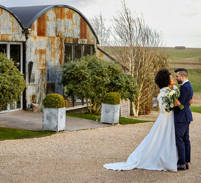 Bride & groom stand outside the Stone Barn Cotswolds for rustic wedding