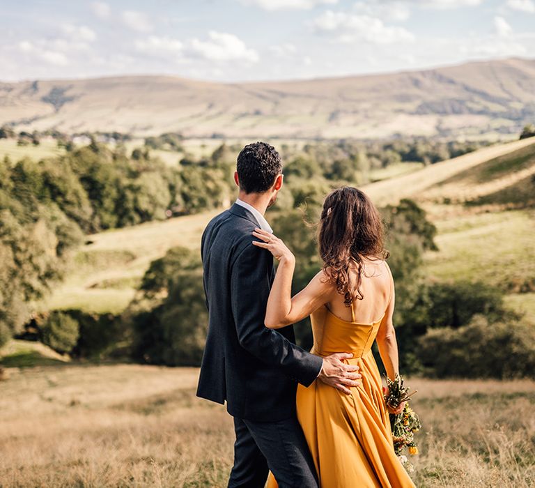 Bride & groom look across hills outdoors on their wedding day