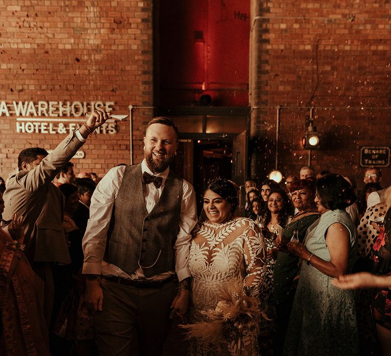 Confetti moment at Victoria Warehouse in Manchester with groom in a tweed waistcoat and bride in a lace Rue De Seine Avril wedding dress