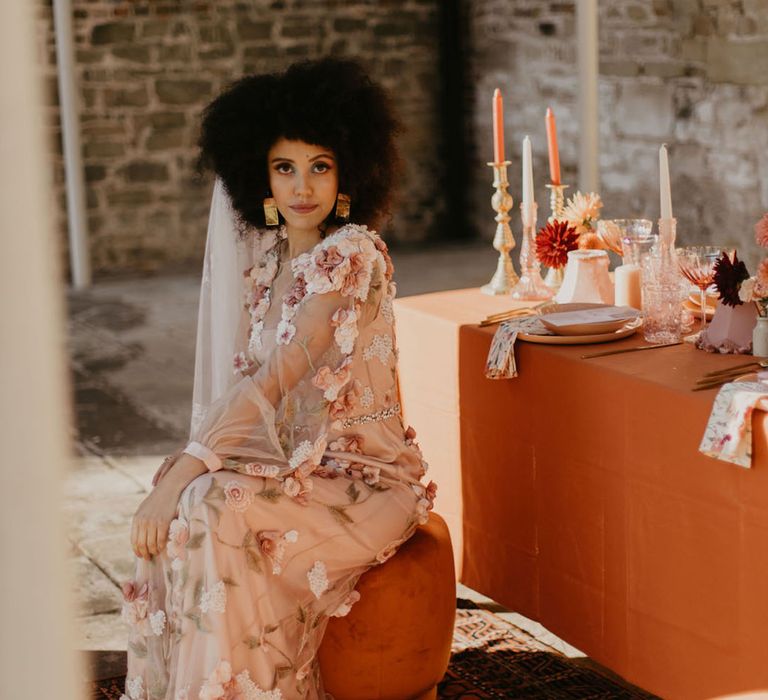 black bride in a 3D flower pink embroidered wedding dress sitting at her outdoor wedding reception at Chiddingstone Castle 