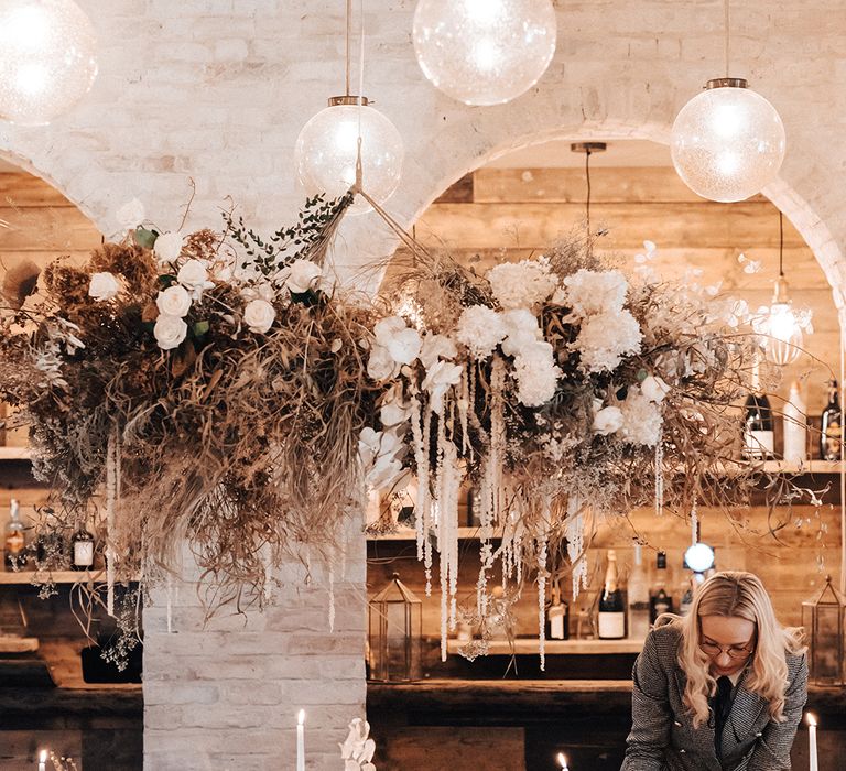 Iscoyd Park coachhouse wedding with dried and fresh white flower installation, flower stems in bottles and taper candles 