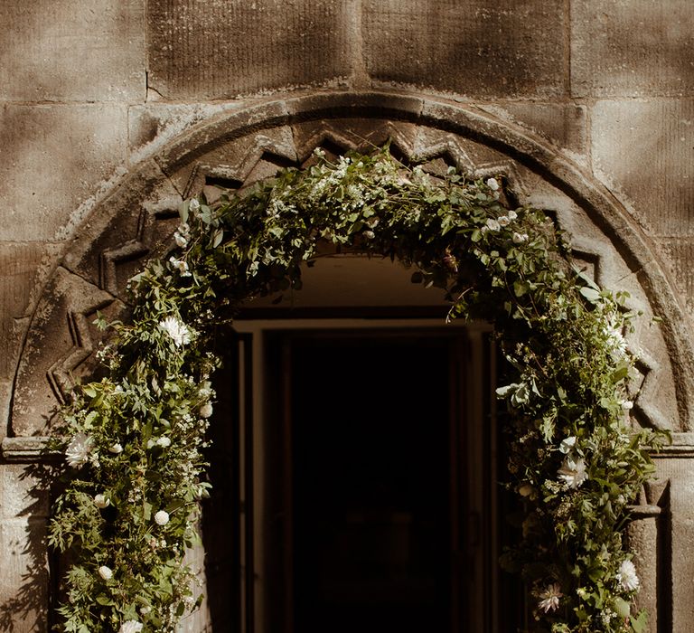 Foliage and white flower archway for entrance into the church for the wedding