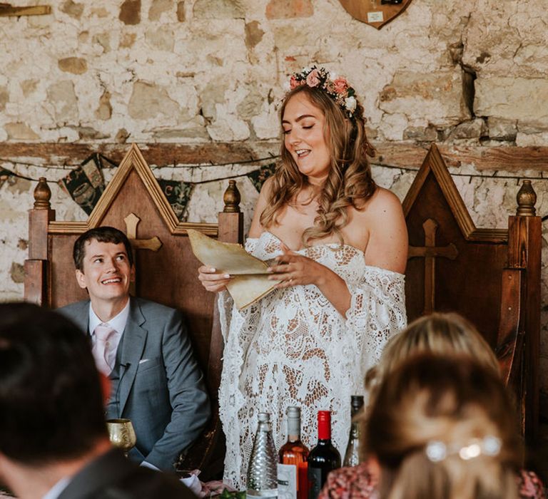 Bride in lace wedding dress holds old parchment to read speech off of for fantasy themed wedding with large wooden thrones