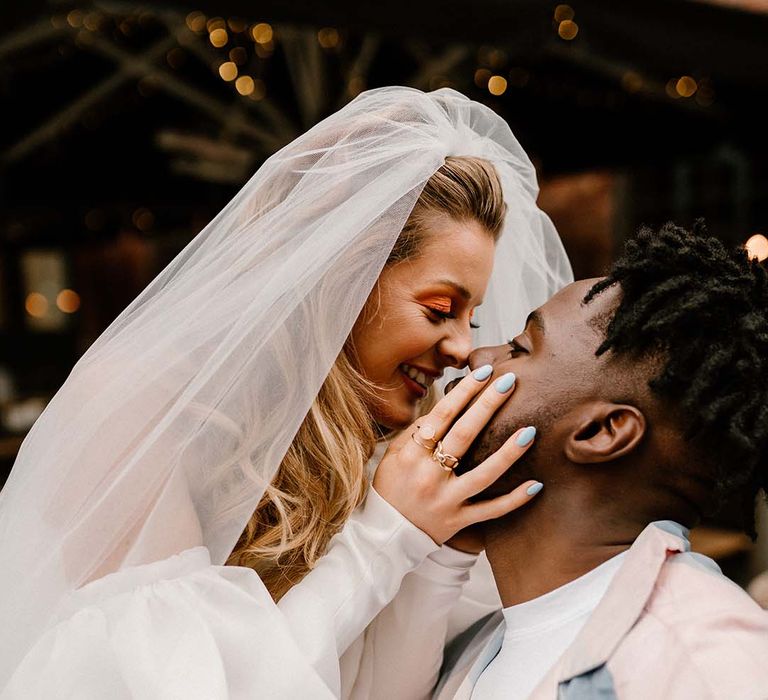 Bride with blue wedding nails holding her grooms face at fun London elopement 