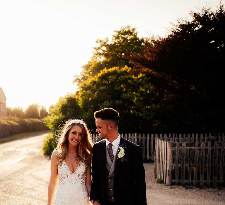 Golden hour shot for bride and groom with bride in lace wedding dress and groom in dark suit