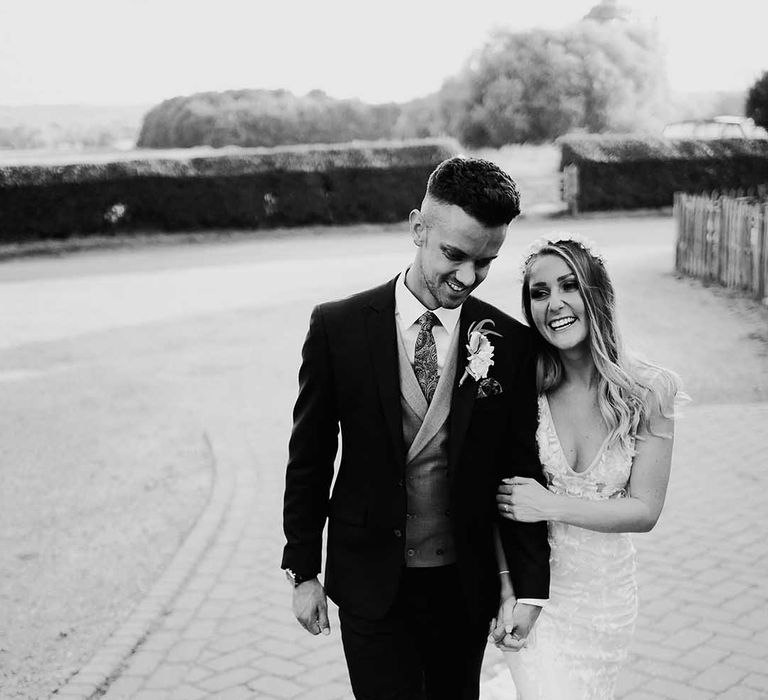 Bride and groom smile and walk hand in hand after their wedding