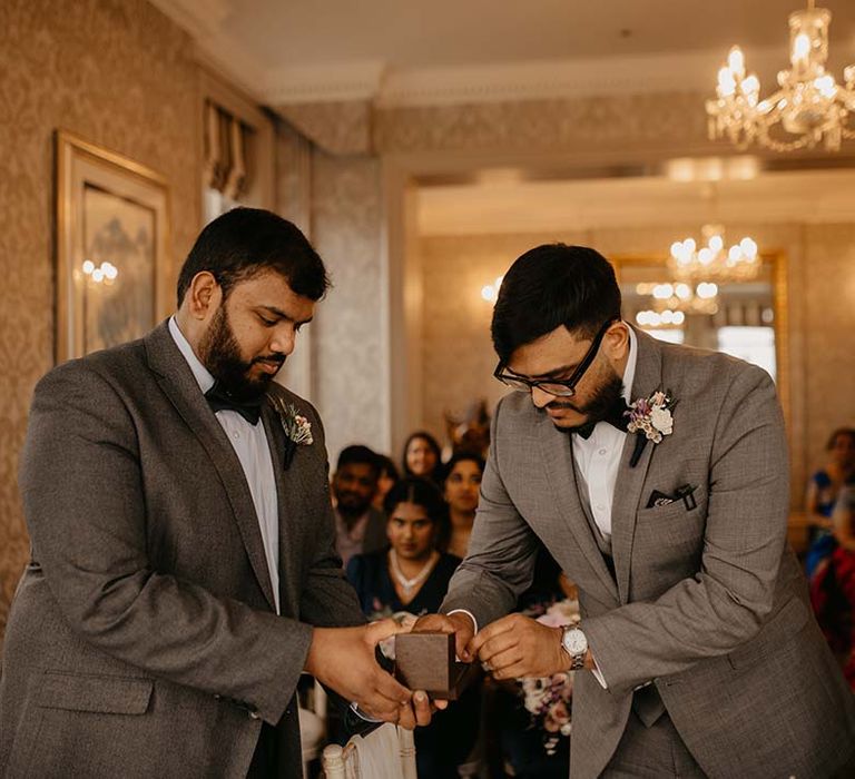 Ring bearer providing the rings to the groom in grey suit with black bow tie at Petersham Hotel 