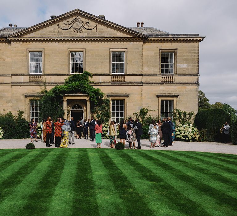 Wedding guests socialise outside of Middleton Lodge wedding venue