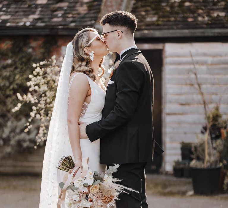 Bride and groom share a kiss as they wear sunglasses on sunny wedding day 