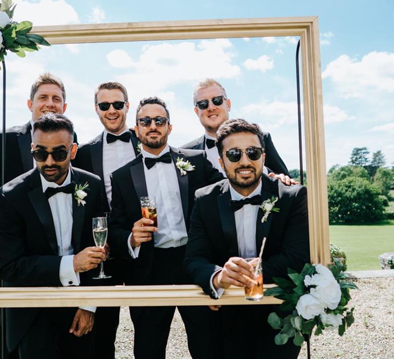 Groomsmen in tuxedos wearing sunglasses at black tie wedding 