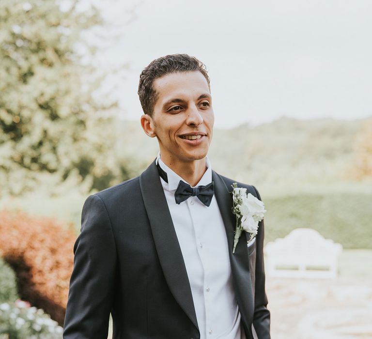 Groom in black tie for classic wedding with white rose buttonhole 