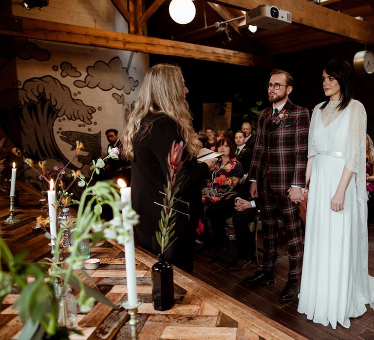 Bride & groom hold hands during wedding ceremony at The Chimney House 