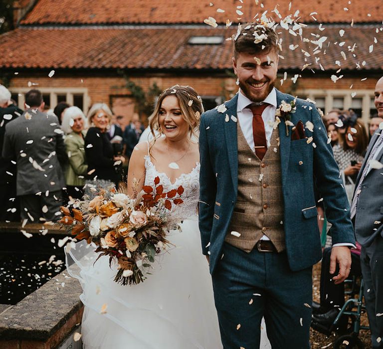 Bride and groom exit their ceremony to white confetti 